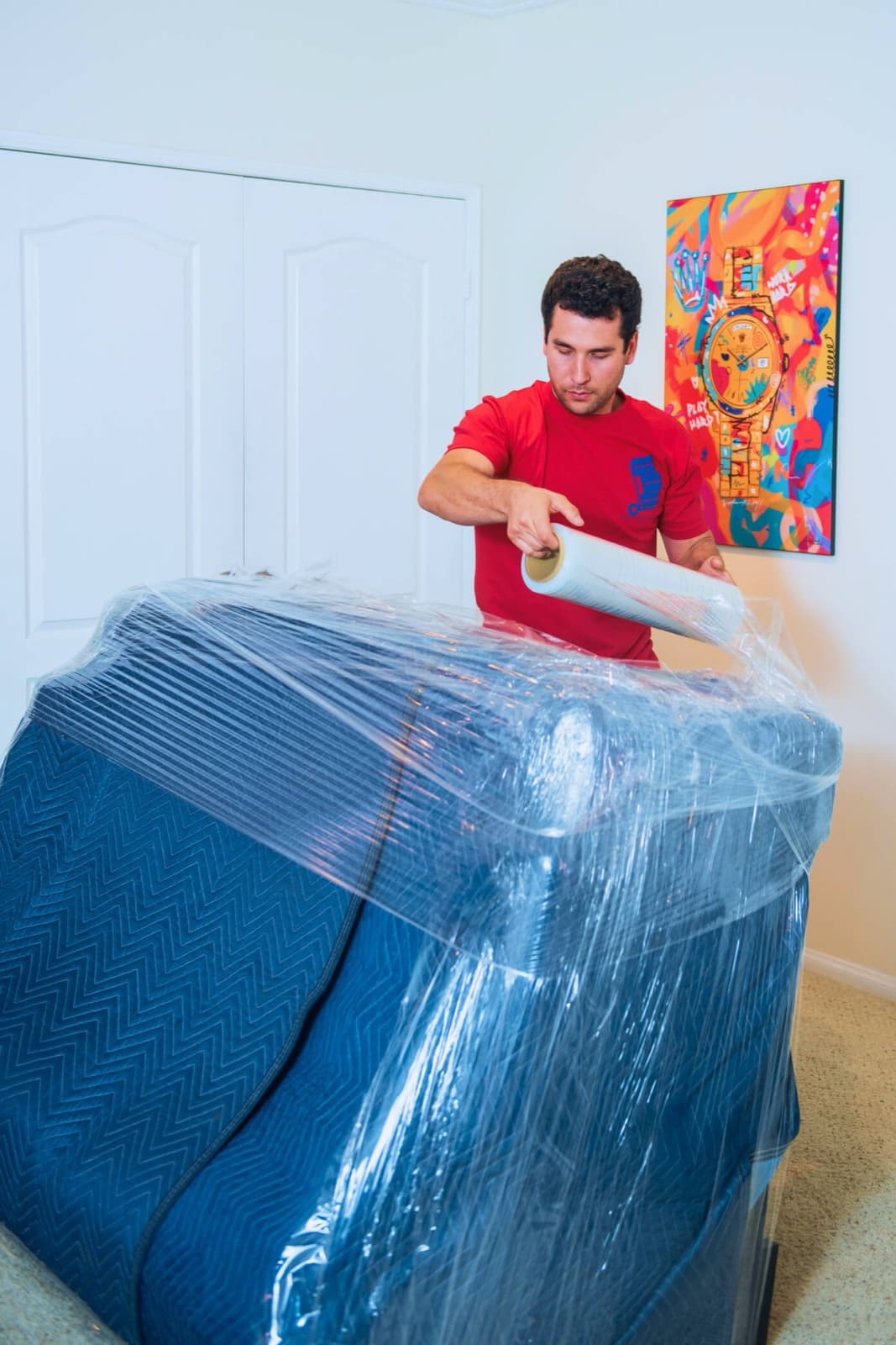 Wrapping a sofa in moving blankets and stretch film